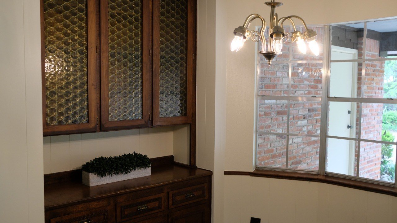 Residential dining area with wood cabinetry, glass doors, and warm pendant lighting.