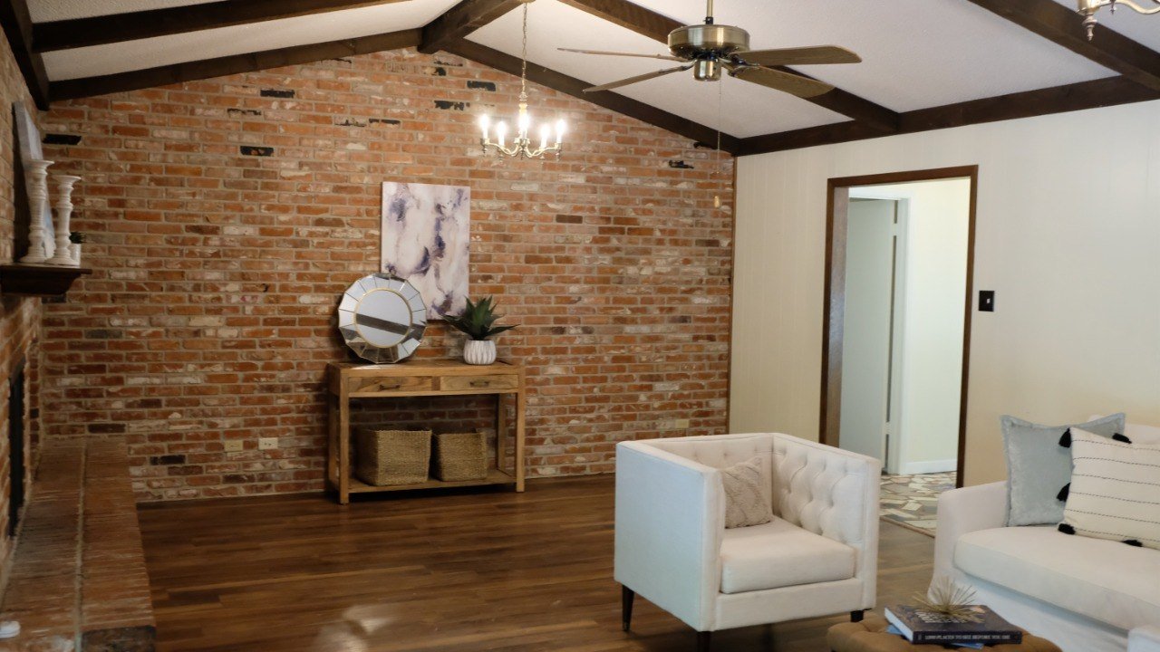Warm residential interior with exposed brick, wood beams, and a white sofa.